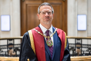 A close up of Tim smiling into the camera wearing RCVS attire